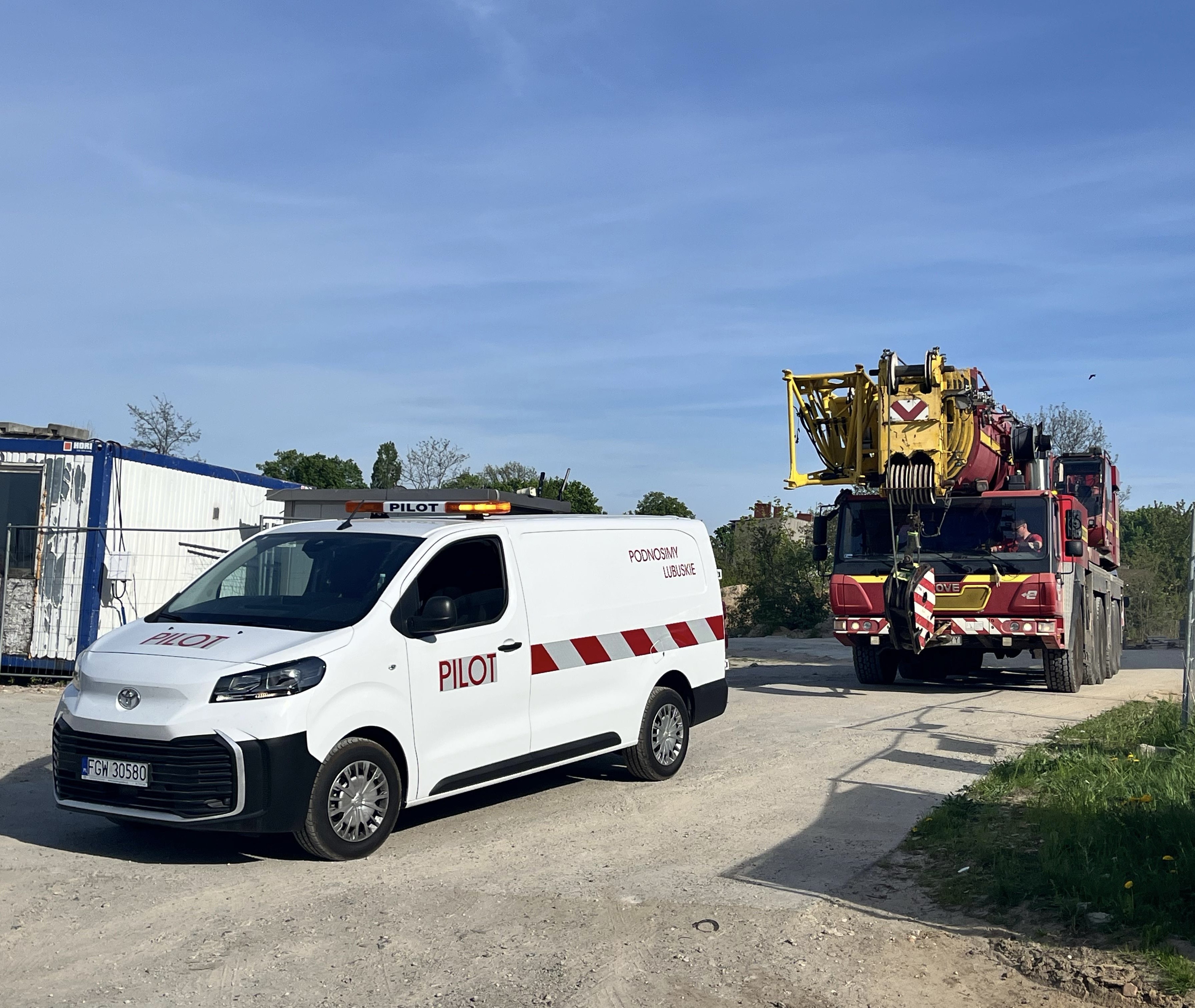 Pojazd pilotujący eskortuje żuraw samojezdny GROVE podczas transportu drogowego na miejsce realizacji zlecenia