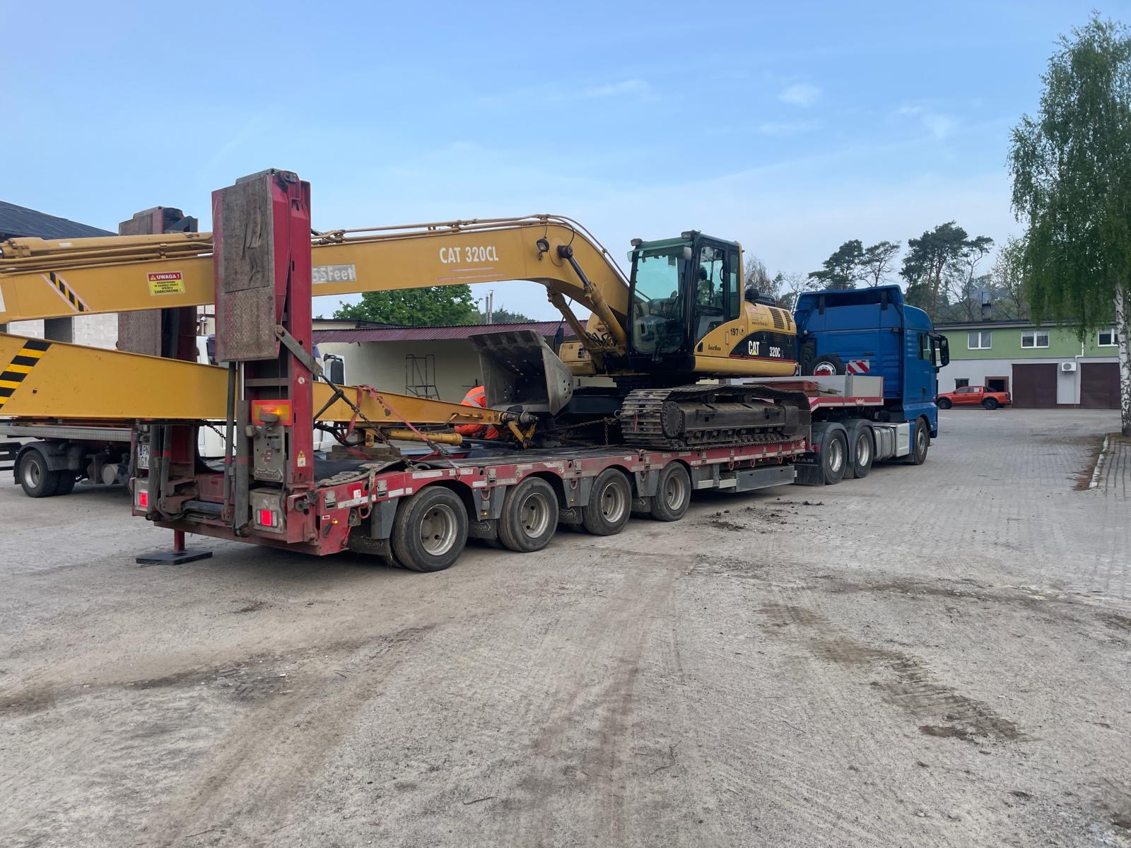Koparka Caterpillar 320CL przewożona na naczepie niskopodwoziowej przez firmę Elektro-Bud